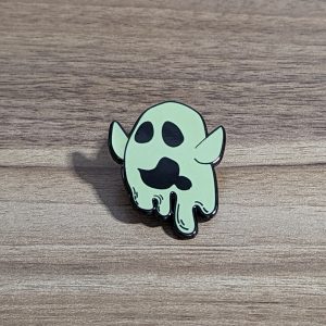Ghost pin with arms high and drooling. Beige colour. Sitting on a wooden background