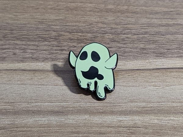 Ghost pin with arms high and drooling. Beige colour. Sitting on a wooden background